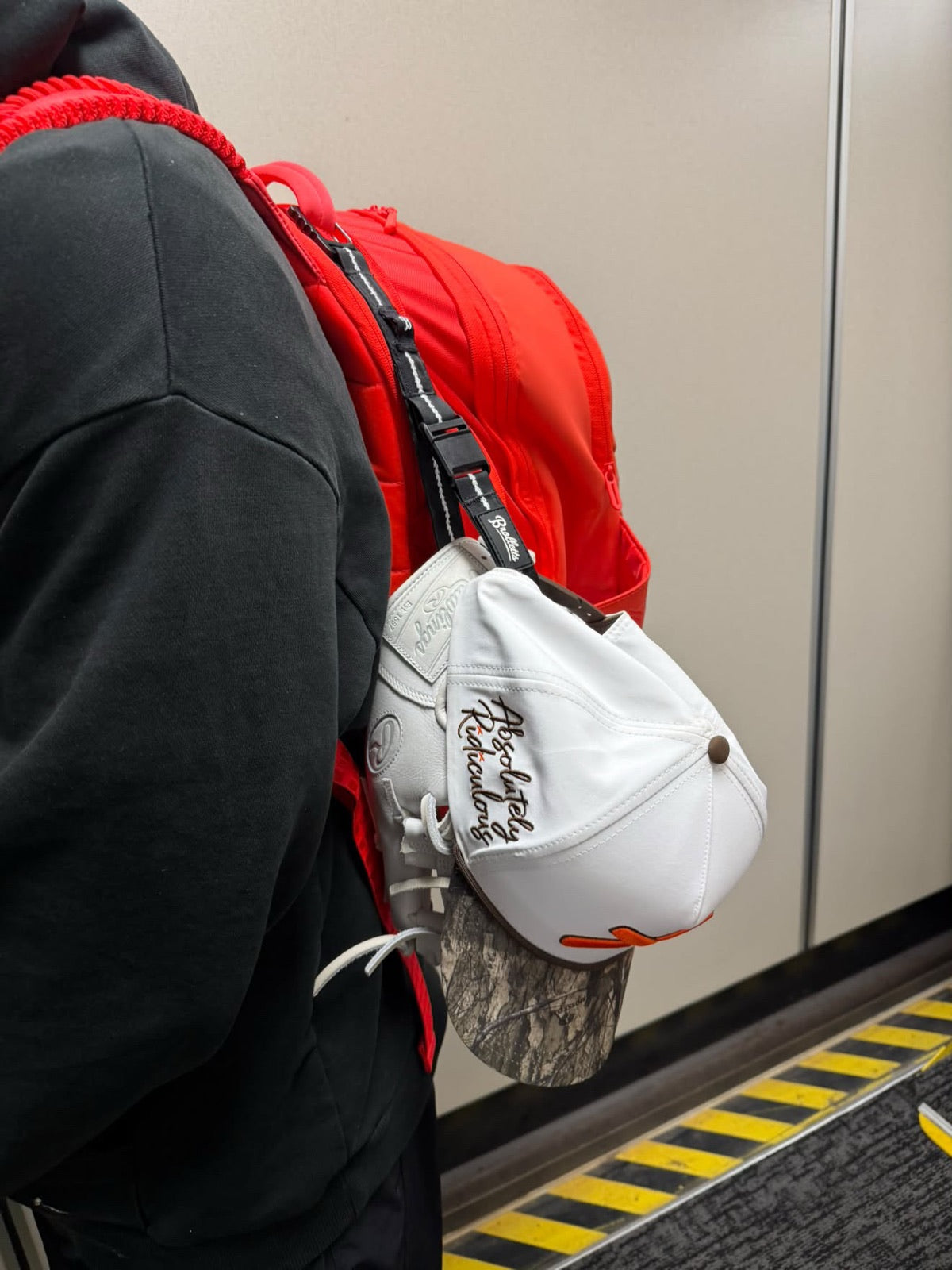 Glove and hat clipped together on the outside of a backpack